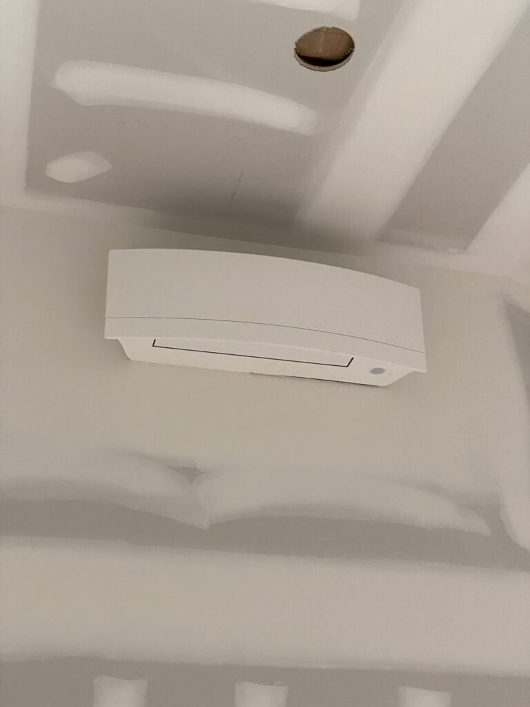 Moon Air technician servicing central AC unit at suburban home exterior