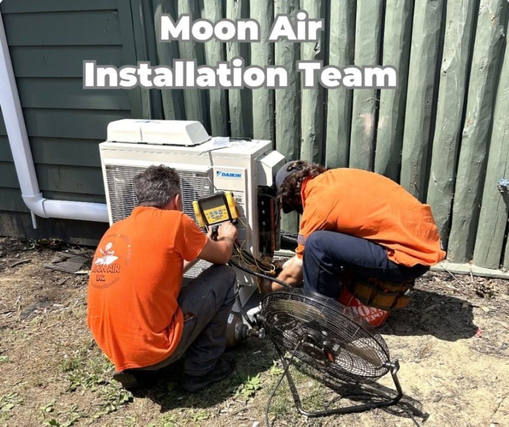 Moon Air technician servicing central AC unit at suburban home exterior