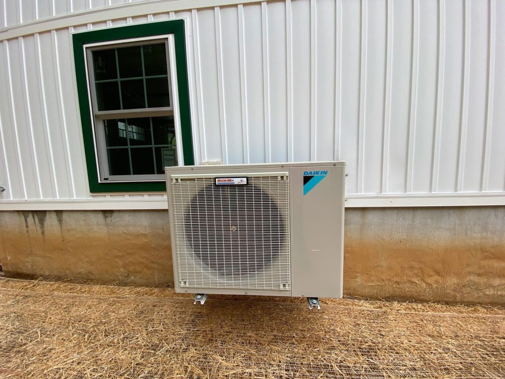 Moon Air technician servicing central AC unit at suburban home exterior